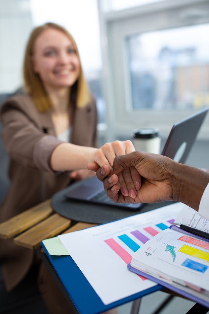 Two business colleagues performing a fist bump in a modern office setting, indicating teamwork.